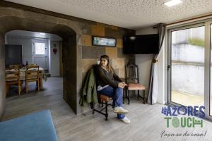 a woman sitting in a chair in a living room at Sunset Pool House in Feteira