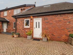 a brick building with a white door and potted plants at The Nook in Wigton