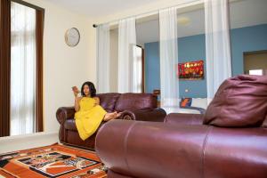Eine Frau in einem gelben Kleid sitzt auf einem Ledersofa. in der Unterkunft Premium HOTEL in Douala
