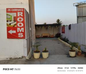 a patio with a sign and potted plants next to a building at Hotel ZB comforts MYSORE in Mysore