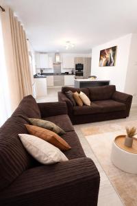 a living room with two brown couches and a kitchen at Ebbsfleet Luxe in Swanscombe
