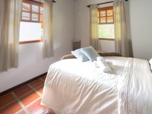 a white bed in a bedroom with two windows at Casarão in Marechal Floriano