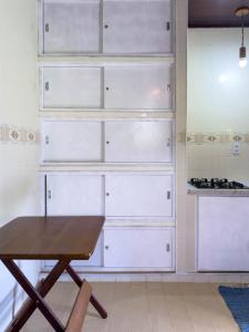 a kitchen with white drawers and a wooden table at Casarão in Marechal Floriano