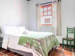 a bedroom with a bed with a green blanket on it at Casarão in Marechal Floriano
