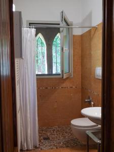 a bathroom with a toilet and a sink and a window at Ai Tigli in Castel dʼArio