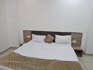 a bedroom with a large bed with white sheets and pillows at Prem Resort in Vrindāvan