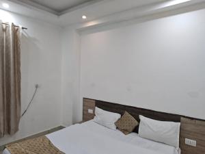 a bedroom with a bed with white sheets and pillows at Prem Resort in Vrindāvan