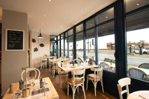 a restaurant with tables and chairs and windows at Hotel Le Richelieu in Le Tréport