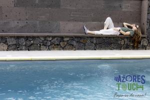 a woman laying on a wall next to a swimming pool at Sunset Pool House T1 in Feteira +3 photos
