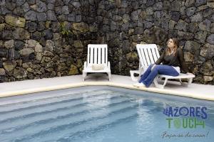a woman sitting in chairs next to a swimming pool at Sunset Pool House T1 in Feteira