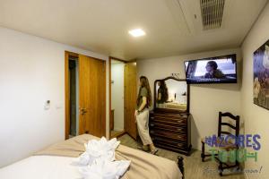 a woman standing in a room with a tv in a bedroom at Sunset Pool House T1 in Feteira