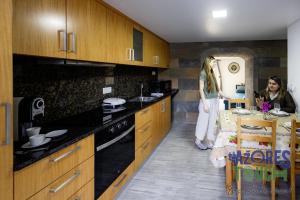 a woman standing in a kitchen with a woman standing next to a table at Sunset Pool House T1 in Feteira