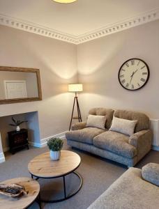 a living room with a couch and a clock on the wall at HORSEMARKET on the square in Kelso