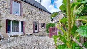 a stone house with a patio and chairs outside at La Ferrandaise in Chambon-sur-Lac