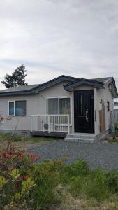 a white house with a black door and a porch at Aioi house in Tsubetsu