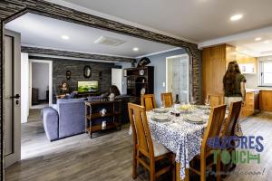 a dining room and living room with a table and chairs at Sunset Pool House T2 in Feteira