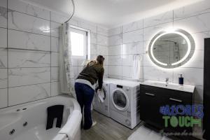 a woman standing in a bathroom with a washing machine at Sunset Pool House T2 in Feteira