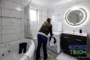 a woman standing in a bathroom next to a tub at Sunset Pool House T2 in Feteira +9 photos