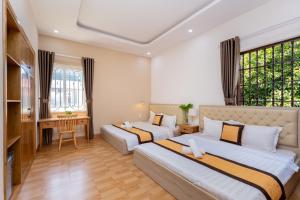 a hotel room with two beds and a desk at Villa 25 Lạc Long Quân in Vung Tau