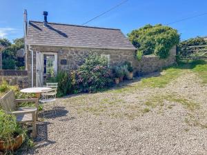 a stone cottage with a table and chairs in a yard at The Old Studio in Penzance