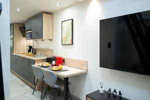 a kitchen with a table with chairs and a television at Studio Le Rubis tout inclus petitdéjeuner in Éloyes