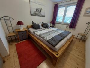 a bedroom with a large bed with a red rug at Birkenquartier in Zingst