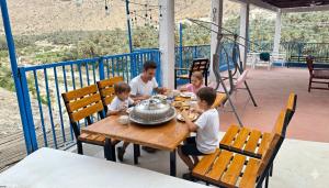 a group of children sitting at a wooden table at Hawer Inn - wadi bani Khalid in Biḑ‘ah +30 photos