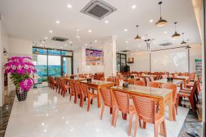 a restaurant with wooden tables and chairs and flowers at Hotel Hải Âu in Sầm Sơn