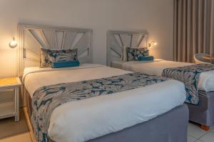 a bedroom with two beds with blue and white sheets at Karibea La Valmenière Hôtel in Fort-de-France