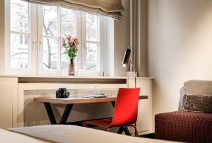 ein Zimmer mit einem Tisch, einem roten Stuhl und einem Fenster in der Unterkunft Apartment040 in Hamburg