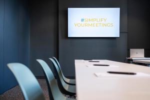 a white table and chairs in a room with a screen at sylc. Apartmenthotel – Serviced Apartments in Hamburg