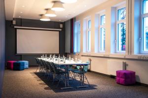 a conference room with a table and chairs and a projection screen at sylc. Apartmenthotel – Serviced Apartments in Hamburg +76 photos