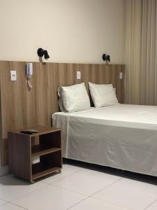 a hotel room with a bed and a night stand at Hotel Oscar Gold Janaúba in Janaúba