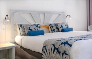 a bedroom with a large white bed with blue pillows at Karibea La Valmenière Hôtel in Fort-de-France