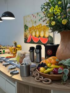 a table with a bowl of fruit and a vase of flowers at Hotel Oscar Gold Janaúba in Janaúba +32 photos
