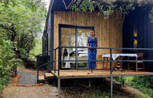 a woman standing on the porch of a tiny house at MaraRiver TreeHouse in Musiara Campsite