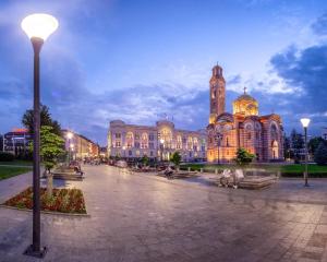 a large building with a clock tower in front of it at Apartmani Stan na dan 34 in Banja Luka