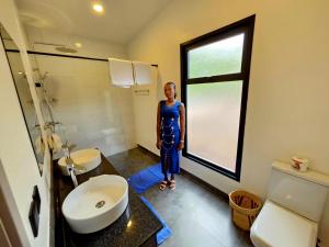 a woman standing in a bathroom with a window at MaraRiver TreeHouse in Musiara Campsite