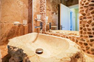 a bathroom with a large stone sink in front of a mirror at Sandra Villa Nea Skioni several steps from the sea in Nea Skioni +37 photos