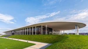 a large building with a grass field in front of it at Setia Alam Urban Rooms in Shah Alam