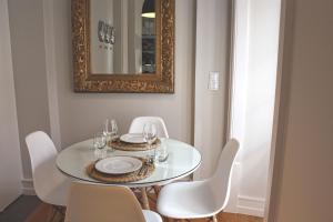 een eettafel met witte stoelen en een spiegel bij Baixa Charming Apt. | Cascão 18 in Lissabon