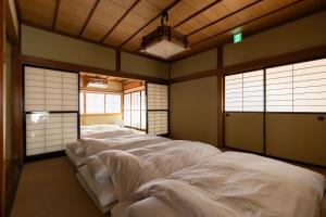 a room with four white beds in it at Arai アライ in Takayama