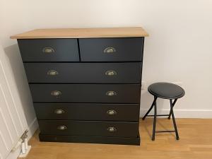 a black dresser with a stool next to it at Citronnelle, 2 Chambres, 3 min Métro 8 in Maisons-Alfort