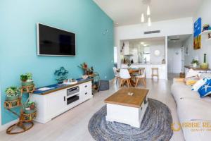 a living room with a couch and a tv on a wall at Sapphire Heaven in Woorim