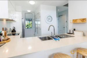 a white kitchen with a sink and a clock on the wall at Sapphire Heaven in Woorim