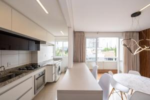 a white kitchen with a table and a dining room at Luxurious 2-Bedroom Duplex with Gourmet Balcony in Goiânia