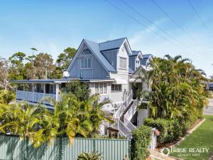 a large white house with palm trees and a fence at BELLA ABODE AND POOL 4 Bedroom Entertainer in Bongaree