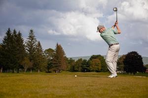 Ein Mann schlägt einen Golfball mit einem Schläger in der Unterkunft Eastwind in Windham