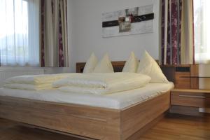 ein Bett mit weißer Bettwäsche und Kissen darauf in der Unterkunft Jasmin in Schladming
