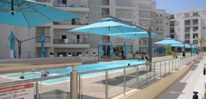 a swimming pool with blue umbrellas and a swimming poolvisor at Fantastic Appartment SeaView Sousse in Akouda +6 photos